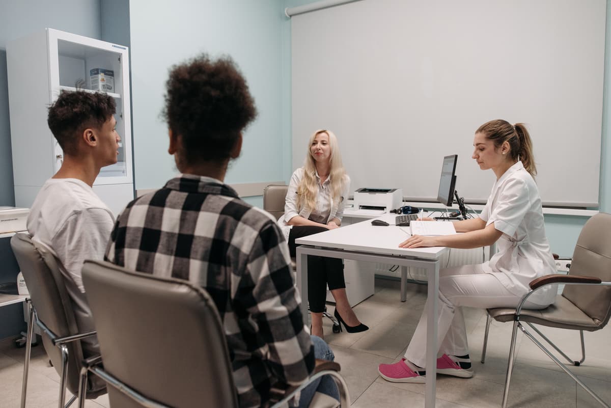 Two people talking with a health professional across a desk