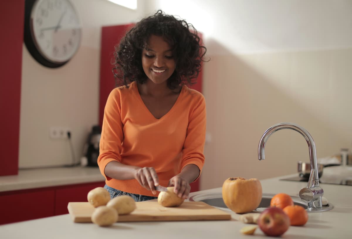 A smiling woman preparing vegetables in her kitchen