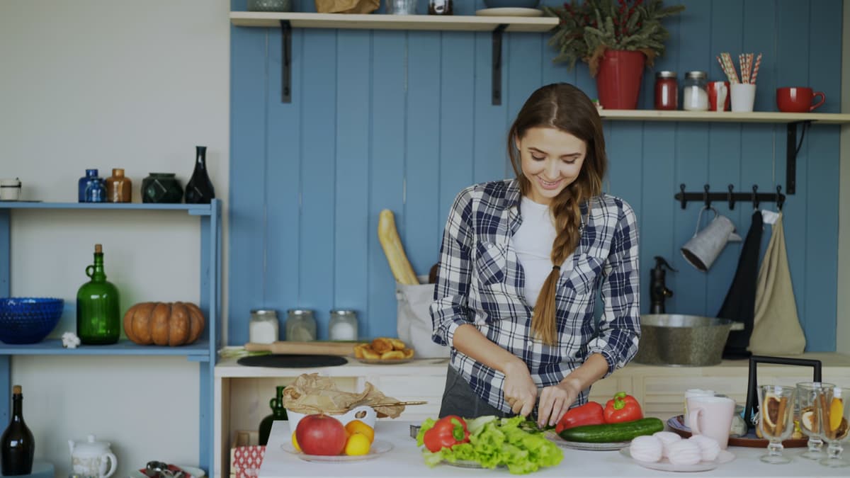 A young woman chopping salad in a home kitchen