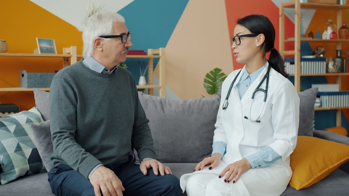 An older man talking with his doctor on a sofa in a consulting room