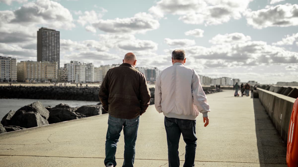 Two older men walking along a seafront promenade