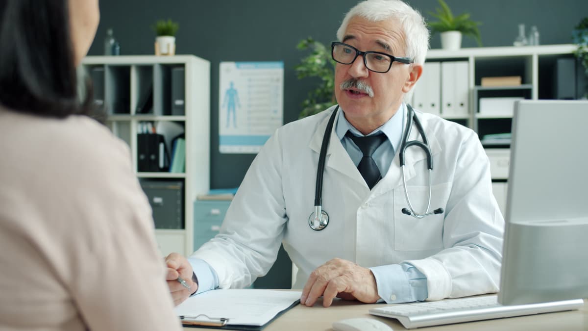 A doctor talking a patient through notes at his desk