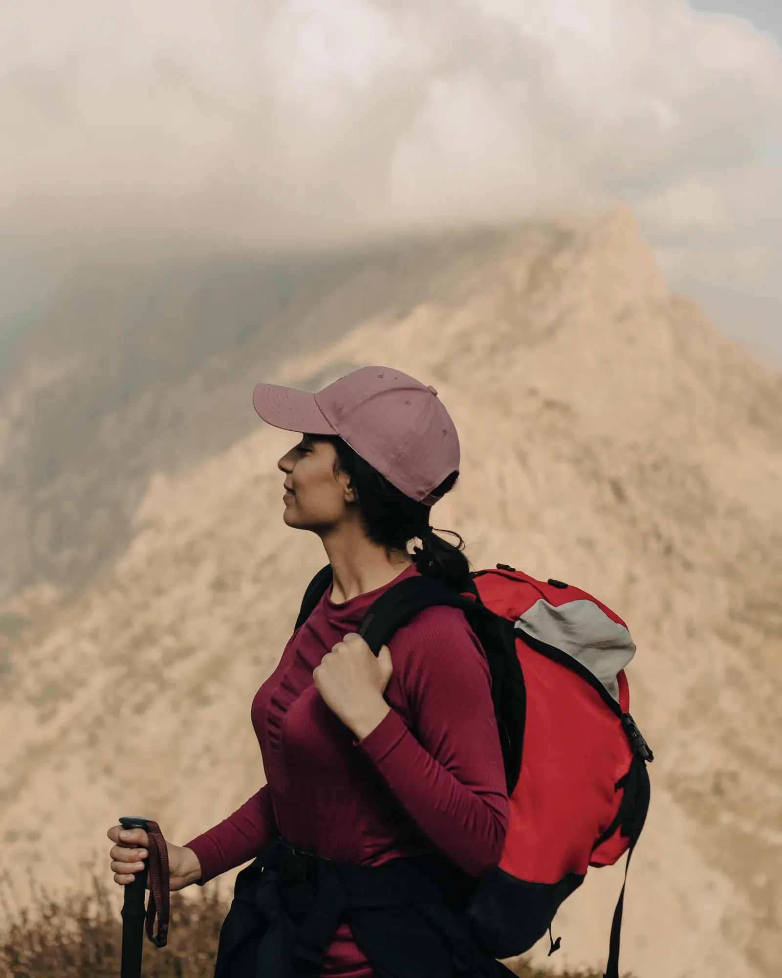 A woman hiking in the mountains with a red backpack
