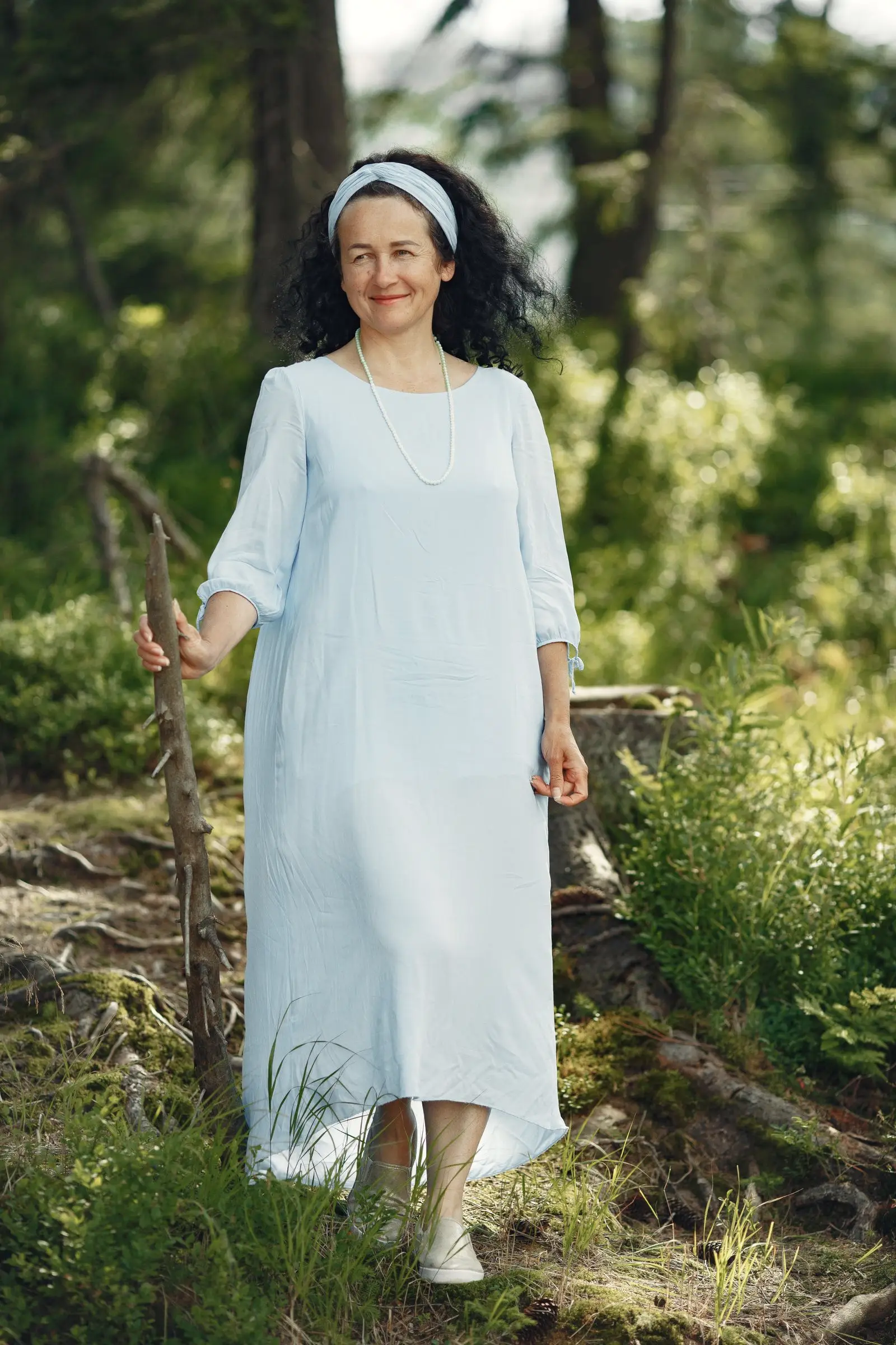 A woman in her fifties smiling in a forest