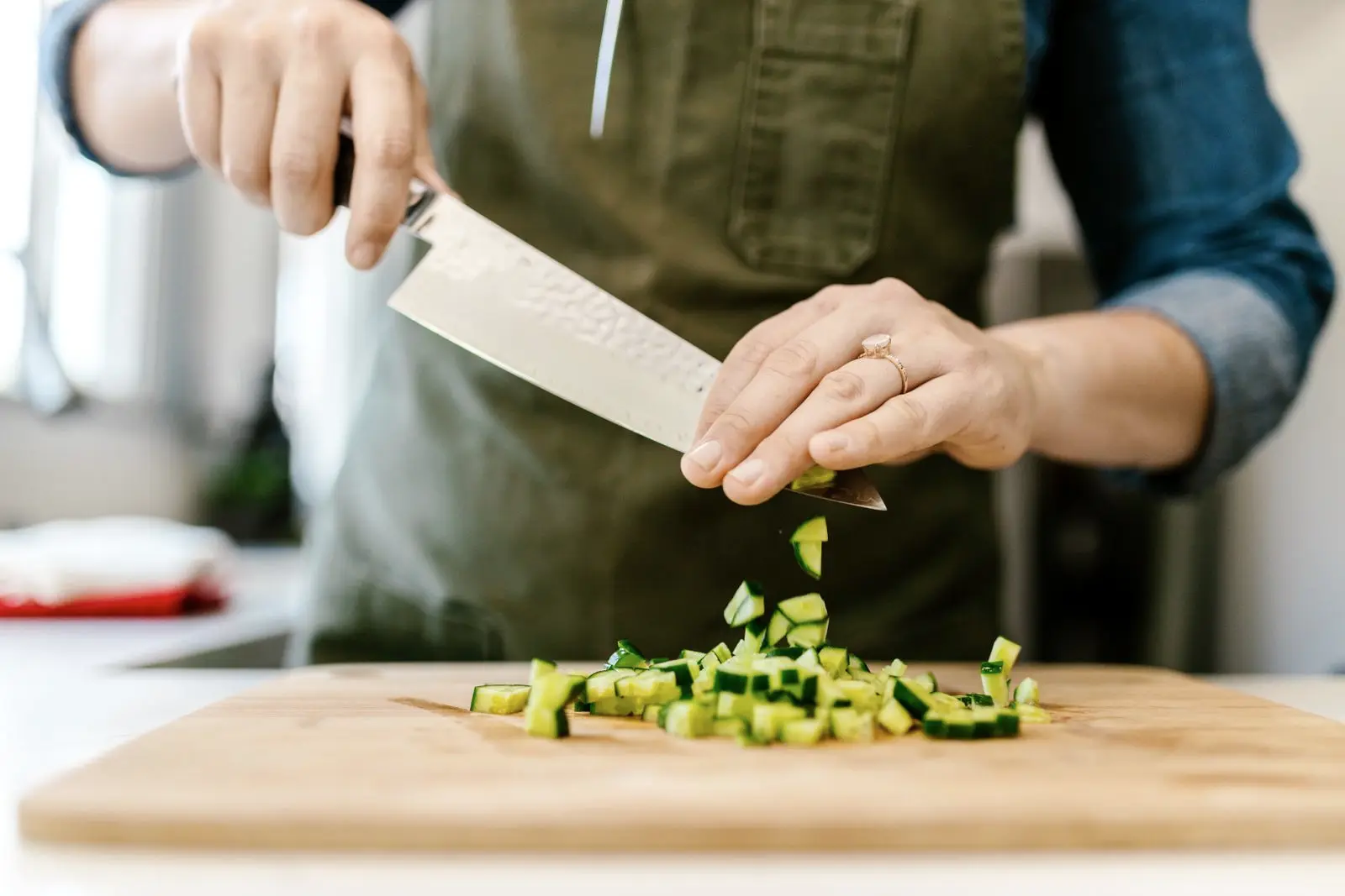 Hands chopping cucumber on a board