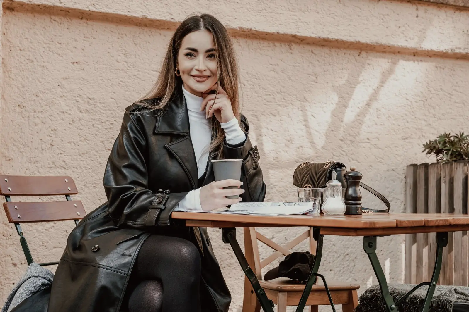 A woman smiling with a coffee at a cafe table