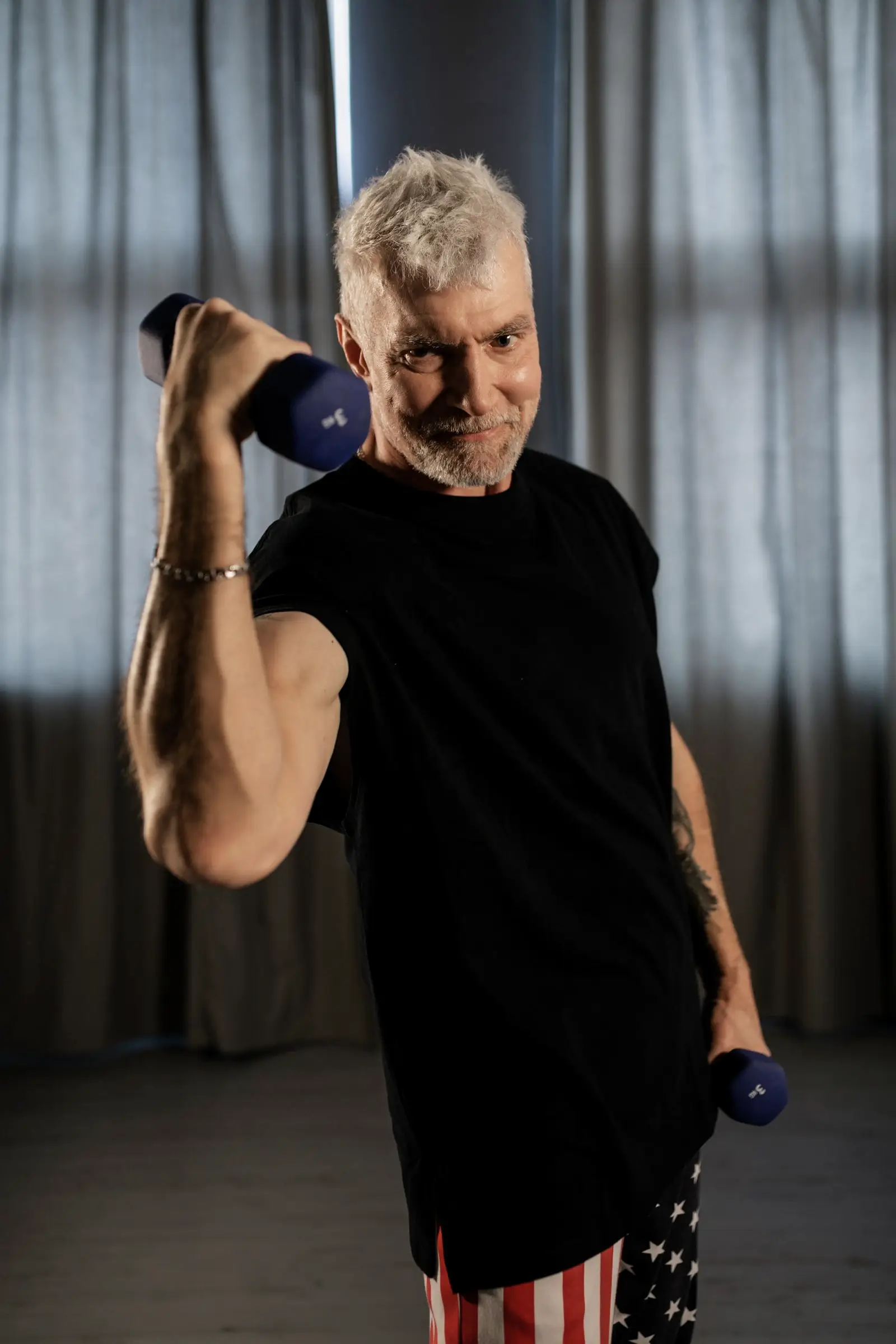A grey-haired man doing dumbbell curls
