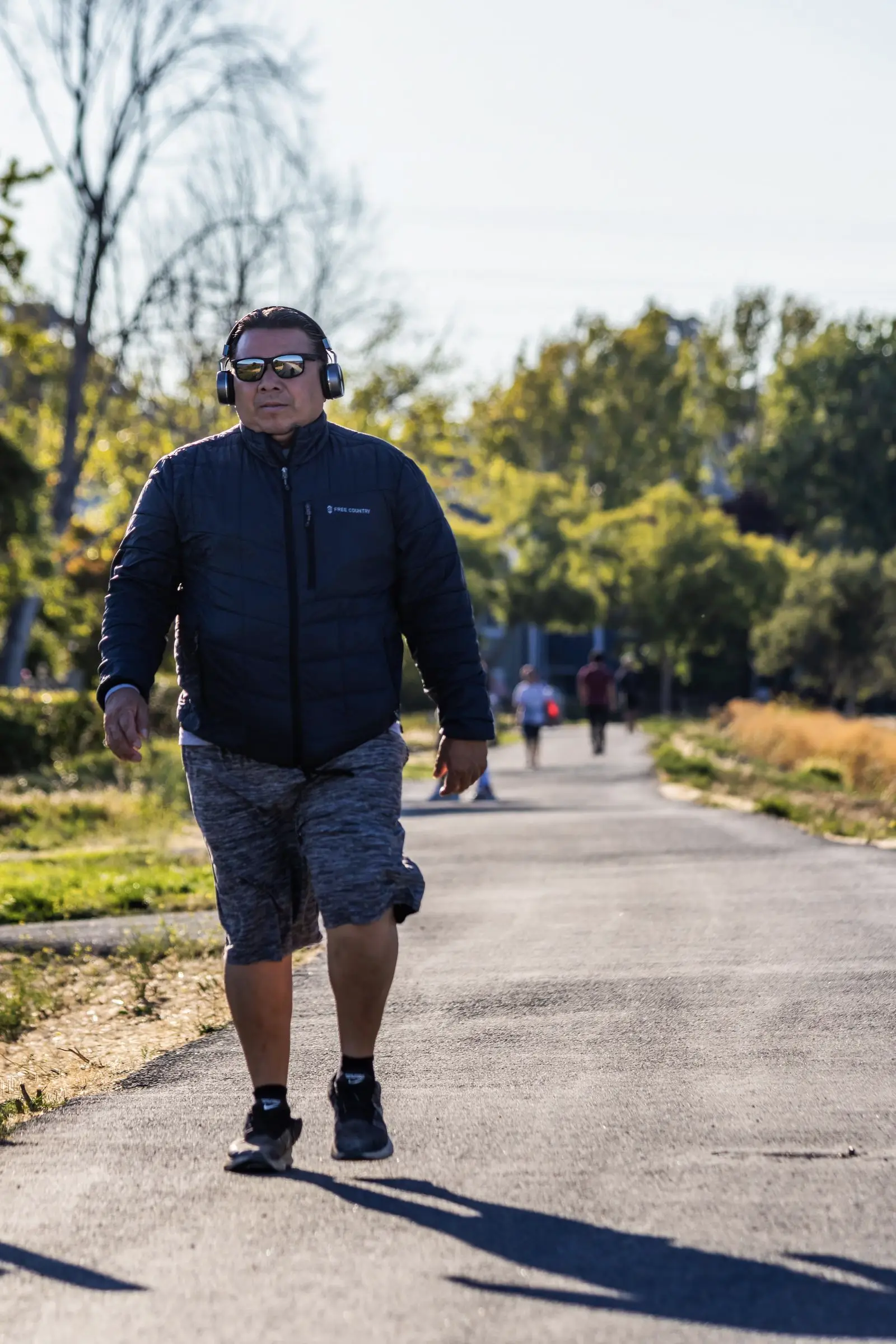 A man walking on a park path with headphones