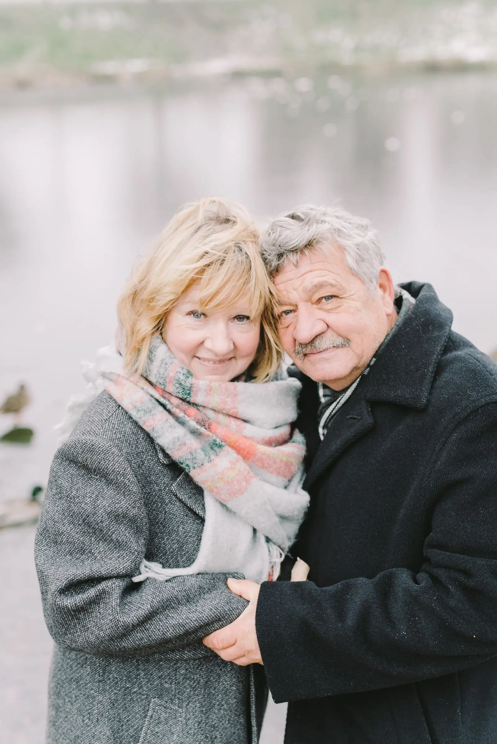 An older couple in scarves smiling cheek to cheek